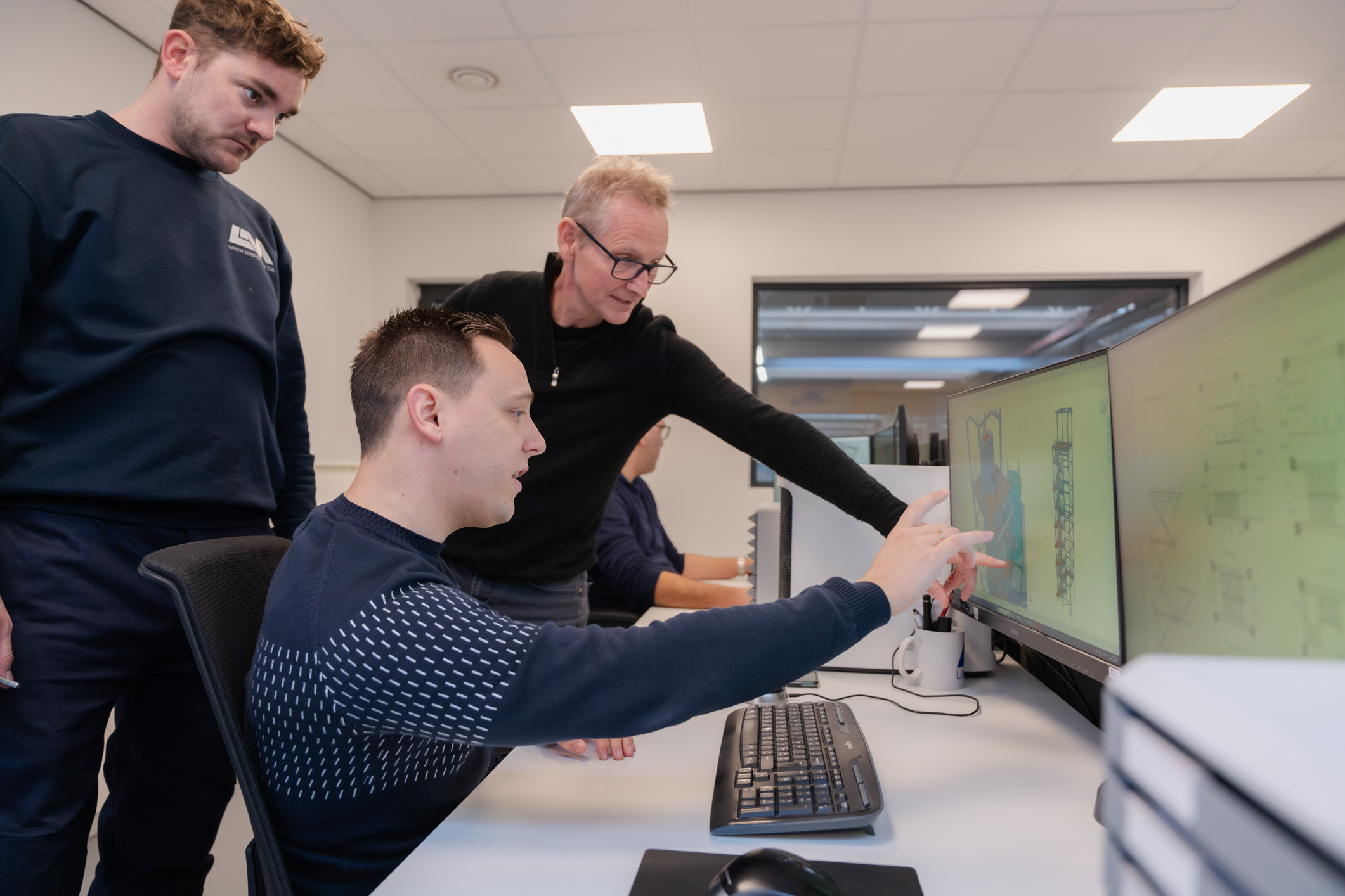 Drie medewerkers overleggen plannen bij een computer.